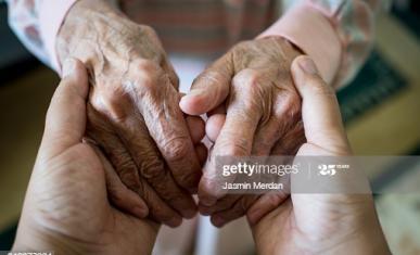 Gros plan sur les mains d'une personne âgée tenues par les mains d'une personne plus jeune