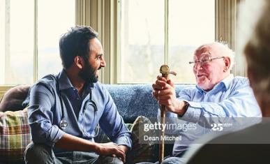 Un homme jeune est en train de rire avec un homme âgé sous le regard d'une femme âgée