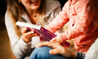 Un enfant lit un livre avec un parent