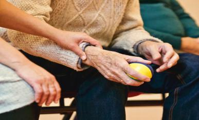 Une personne prend soin d'une personnes âgées en le touchant.