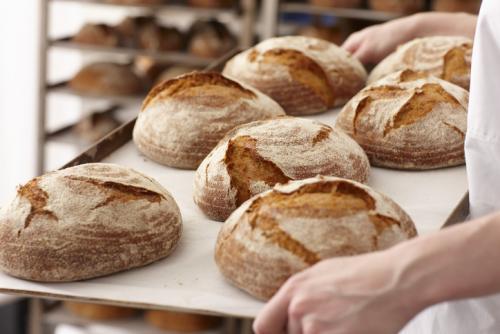 Un boulanger sort du four des boules de pain