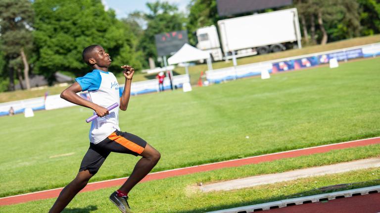 Un sportif en plein sprint dans un stade d'athlétisme