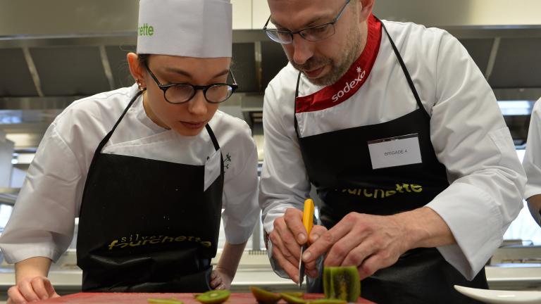 Un cuisinier montre un geste pro à une apprentie