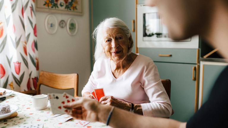 Une personne âgée joue aux cartes chez elle