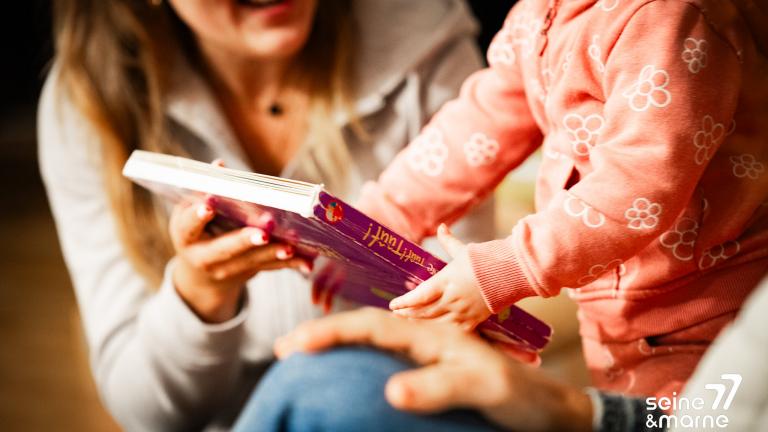 Un enfant lit un livre avec un parent