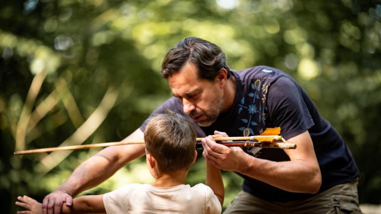 Un médiateur apprend à un enfant à tirer comme les hommes préhistoriques